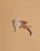 The Maileg Fairy Mouse, Little - Rose features soft wings and large ears, suspended by a thin string to inspire imaginative play against a plain beige background.