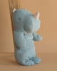 The Maileg Medium Rhino - Dusty Blue, featuring a soft white horn, sits upright against a wooden plank on a beige background, ready to join your collection of Safari friends.