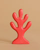 A red, abstract, tree-shaped sculpture with five rounded branches stands upright against a plain beige background, evoking the whimsical style of the Handmade Holzwald Mermaid Set.