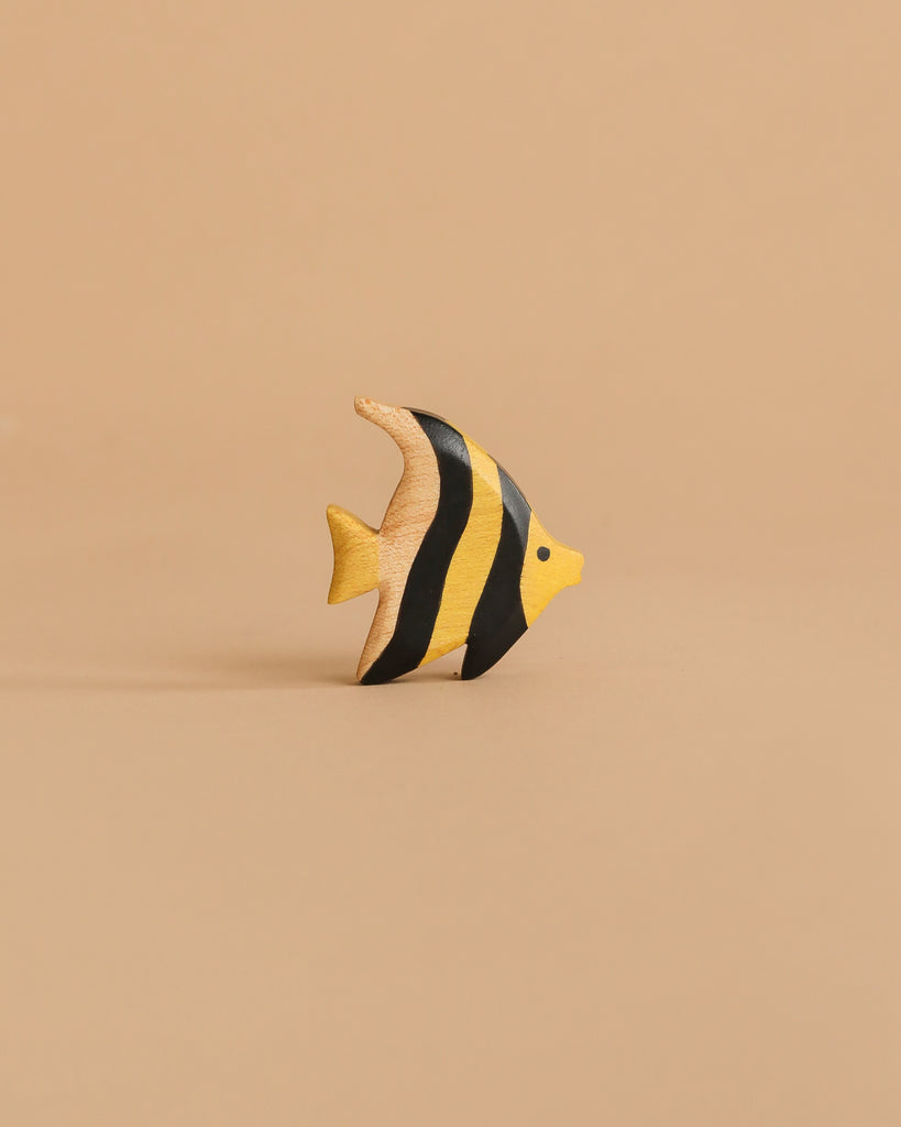 This yellow, black-striped toy fish stands upright on a beige background—a charming piece from the Handmade Holzwald Underwater World Set, perfect as an educational wooden sea animal toy.
