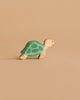 The Handmade Holzwald Sea Turtle is a small wooden toy featuring a green shell and beige body, set against a plain light brown background. Ideal for collections of underwater play figures.