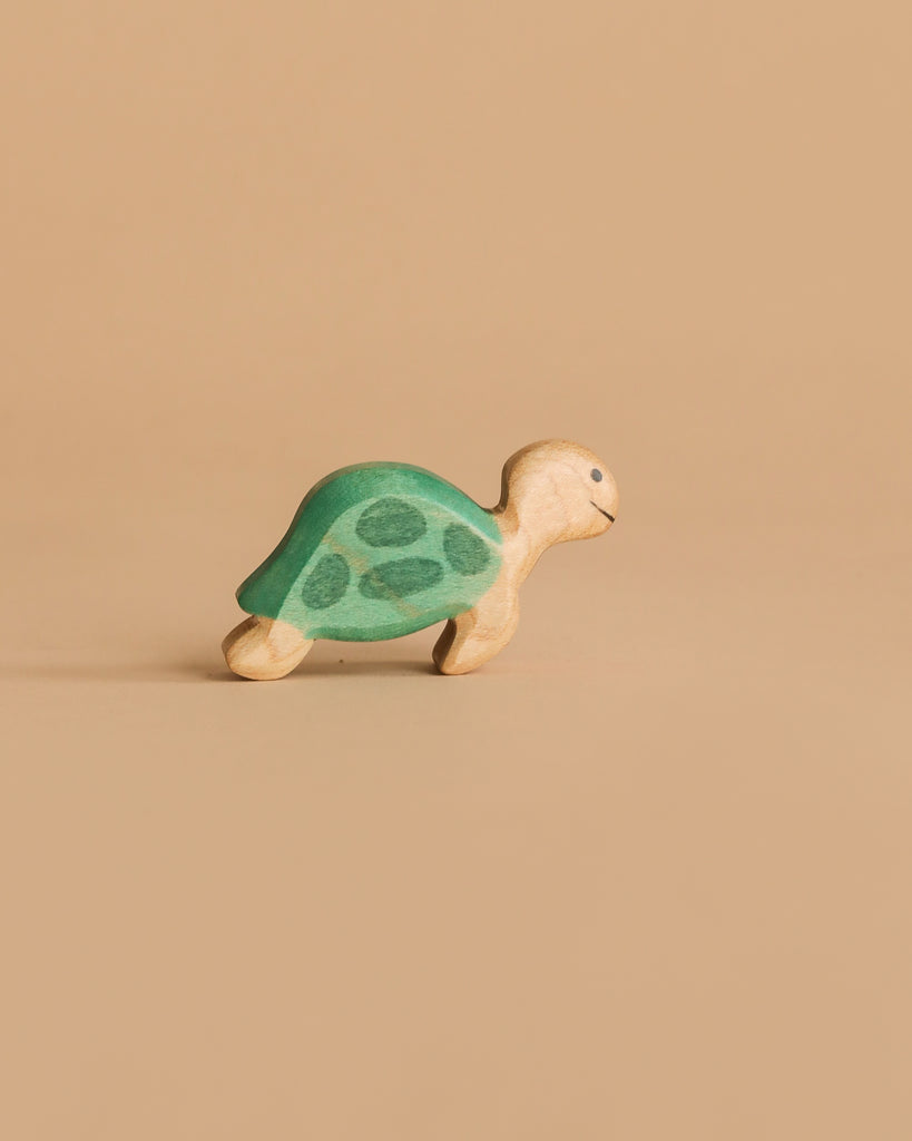 The Handmade Holzwald Sea Turtle is a small wooden toy featuring a green shell and beige body, set against a plain light brown background. Ideal for collections of underwater play figures.