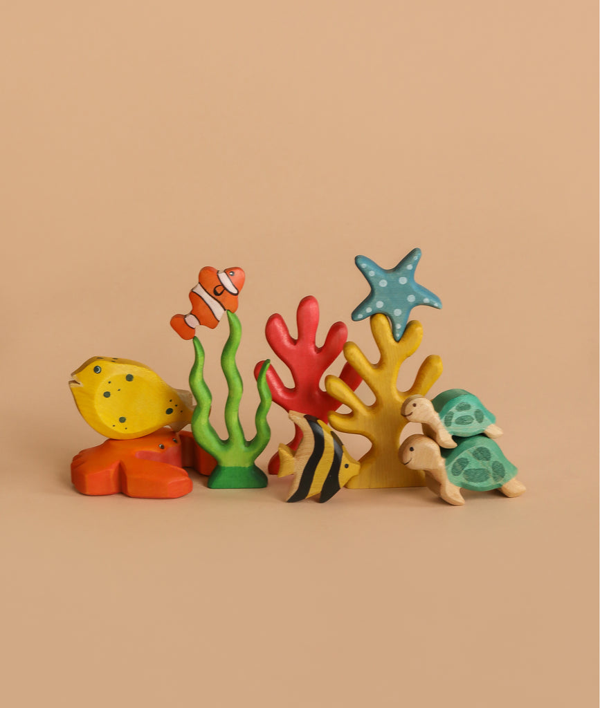 Handmade Holzwald Red Coral—vibrant wooden coral paired with colorful sea animals like yellow fish, clownfish, turtle, and starfish—perfect for underwater play and beautifully displayed on a light tan background.