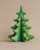 A handmade, three-dimensional puzzle shaped like a Extra Large Wooden Sugar Pine Tree, painted in different shades of green with non-toxic paint against a beige background.
