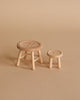 The Maileg Cozy Evening with Granddad Set includes two small wooden stools—one four-legged with a crossbar and one three-legged—ideal as Maileg mouse accessories or dollhouse furniture, both placed on a beige surface.