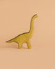 The Handmade Holzwald Brachiosaurus - Green, a wooden toy dinosaur with a long neck and tail, stands on a light beige background—ideal for imaginative play and fostering love for sustainable toys.