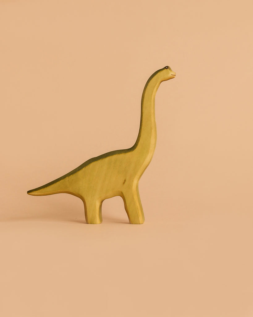 The Handmade Holzwald Brachiosaurus - Green, a wooden toy dinosaur with a long neck and tail, stands on a light beige background—ideal for imaginative play and fostering love for sustainable toys.