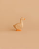 A small, Handmade Holzwald Goose with an orange beak and base stands against a plain, light tan background—perfect for those who appreciate sustainable toys.