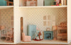 The Maileg Fully Furnished Dollhouse Set + Surprise Gift features a charming dollhouse interior complete with pastel-colored furniture, patterned wallpaper, cozy bunk beds, a classic rocking chair, and a toy mouse riding a wooden rocking horse as the centerpiece, bringing the enchanting world of miniatures to life.