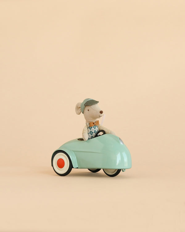 A Maileg Little Brother Driver Set features a small mouse wearing a blue cap and vest, sitting in a light blue toy car with white and orange wheels against a plain beige background.