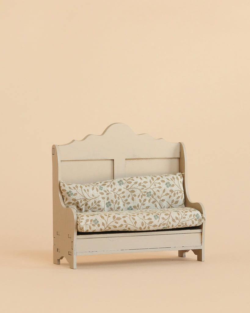 A Maileg Cozy Corner Set, featuring a small vintage-style bench with a scalloped backrest and a floral-patterned cushion, sits against a plain beige background.