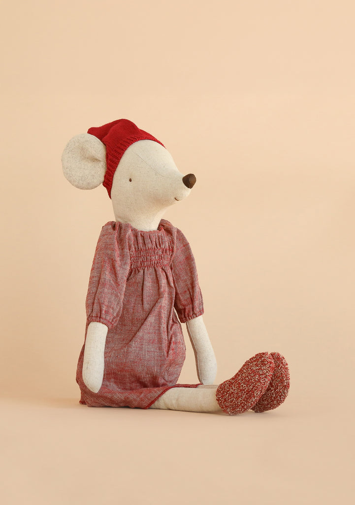 The Maileg Christmas Mouse, Maxi - Girl sits upright against a plain beige background, dressed in a red dress, cozy Christmas hat, and red slippers.