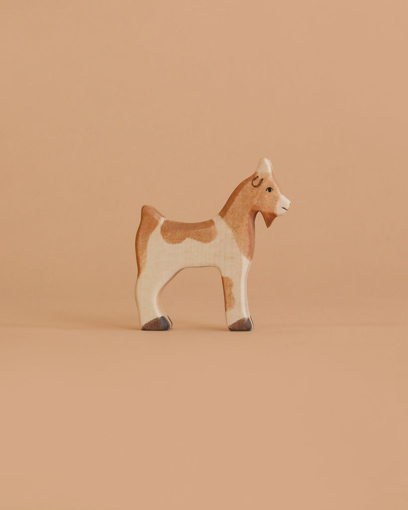 The Holztiger Goat is a small, handcrafted wooden toy with brown and white markings, a simple hand-painted design, and a friendly expression—just like classic HOLZTIGER figures made in Europe.