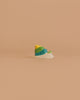 A small, colorful object with layered hues sits on a beige background, reflecting the charm of the Holztiger Handmade Wooden Sea Animals Set crafted from maple and beech wood.