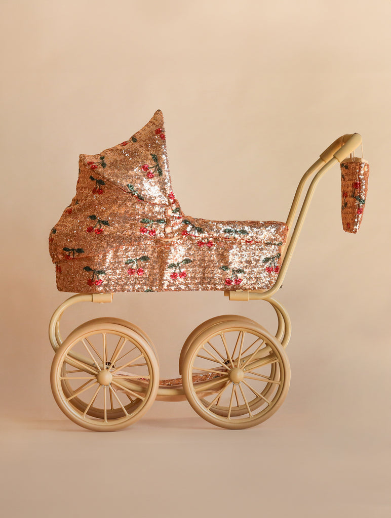 Konges Sloejd Mini Doll Pram - Sparkly Cherry Sequin with a sequined carriage featuring a cherry pattern, set on a beige frame with four large wheels.