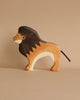Part of the Holztiger Handmade Wooden Safari Animals Set, this wooden lion toy stands proudly with a dark brown mane, light brown body, white underside, and black tail on a neutral beige surface.