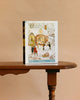A Nor’easter - 750 Piece Jigsaw Puzzle box featuring winter art by Loré Pemberton is displayed upright on a wooden table against a beige background.