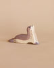 A handcrafted Ostheimer Sea Lion - Head Up sculpture with a natural grain pattern and brown spots, lying on a plain beige background.
