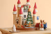 Christmas Castle Music Box shaped like a castle with red-roofed towers, a central Christmas tree with golden garland, and a small reindeer figure.