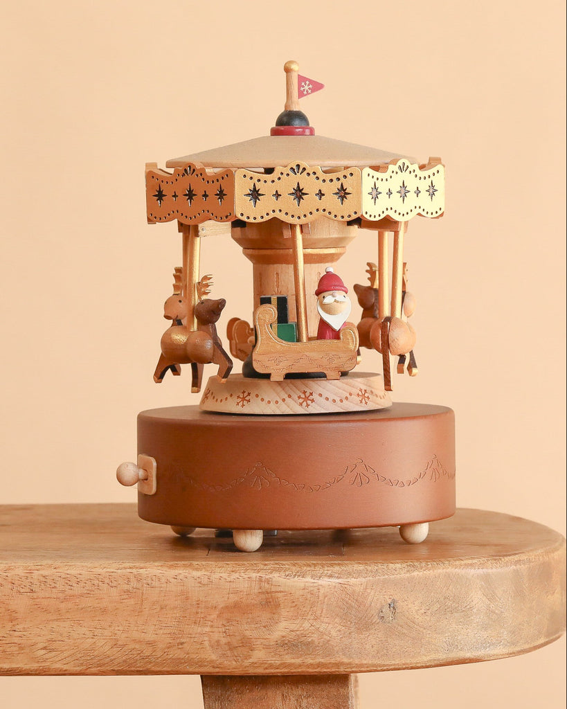 Christmas Carousel Music Box featuring a decorative wooden carousel with miniature reindeer and Santa in a sleigh, resting on a wooden surface.