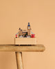 The London Music Box, featuring iconic London landmarks such as Big Ben, a red bus, and a phone booth, sits on a wooden stool against a plain beige background.