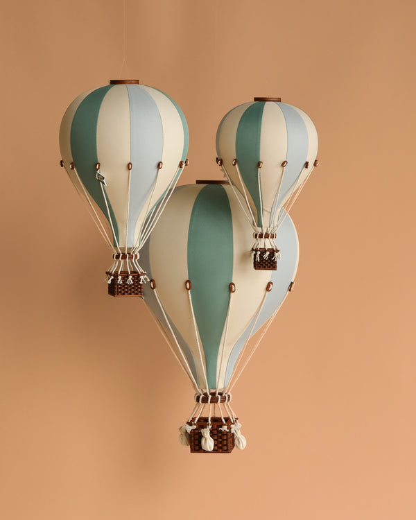 A decorative hot air balloon in mint green and grey hangs against a solid background. This handmade children's room decor features a wooden basket, adding whimsical vintage charm to any space.