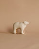 A minimalist wooden sculpture of a polar bear on a beige background. With an abstract, handcrafted toy-like style, it features smooth, rounded edges and a glossy finish. Product: Handmade Wooden Polar Bear.