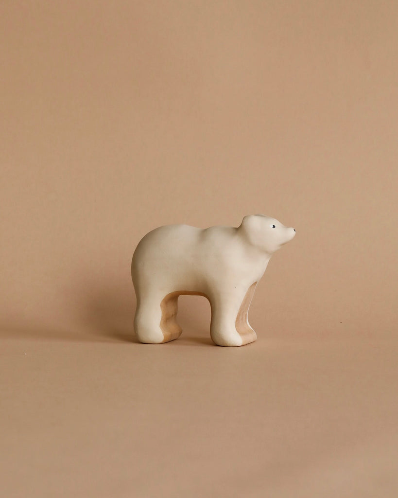 A minimalist wooden sculpture of a polar bear on a beige background. With an abstract, handcrafted toy-like style, it features smooth, rounded edges and a glossy finish. Product: Handmade Wooden Polar Bear.
