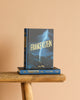 A Frankenstein | Wordsworth Collector's Edition | Hardcover with a lightning bolt cover stands upright on a rustic wooden bench, another copy lying flat below it, all set against a plain beige background.