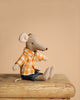 A Maileg Family Celebration Set features a stuffed mouse toy wearing a yellow plaid shirt and blue jeans, sitting on a wooden surface against a plain beige background.