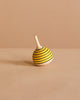 The Spinning Top - Bumble Bee, crafted from maple wood with yellow and black stripes, sits tilted on a plain beige surface against a matching beige background.