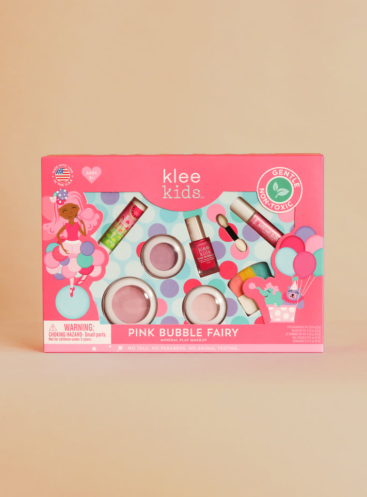 The Klee Naturals Deluxe Makeup Kit - Pink Bubble Fairy features nail polish, lip shimmer, eye shadows, blush, and a brush, all packaged in a pink box with cartoon illustrations.