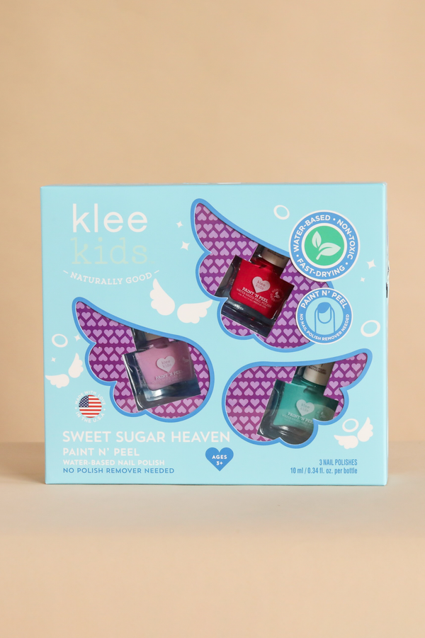 A light blue gift box of Klee Kids Water-Based Nail Polish Set - Starry Sky Kiss containing red, pink, and teal peel-off polish, with winged cutouts and icons indicating it is non-toxic, fast-drying, and peelable.