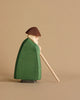 A handcrafted wood figurine of a bearded man wearing a brown hat, green cloak, and holding a wooden staff. The Ostheimer Shepherd With Staff is positioned sideways against a plain beige background, embodying the charm of sustainable materials.