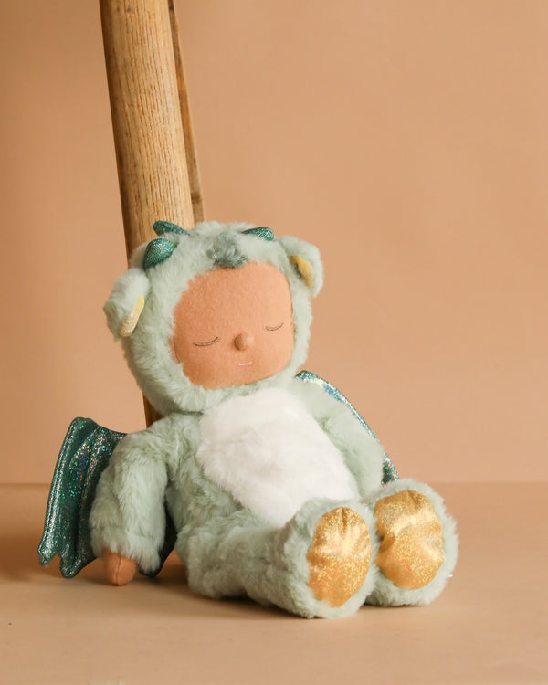 The Olli Ella Cozy Dinkum Dragon - Ash - Green is a soft recycled plush toy with glittery wings and golden feet, dressed in pale green and featuring a peaceful expression—perfect as a weighted cuddle companion.