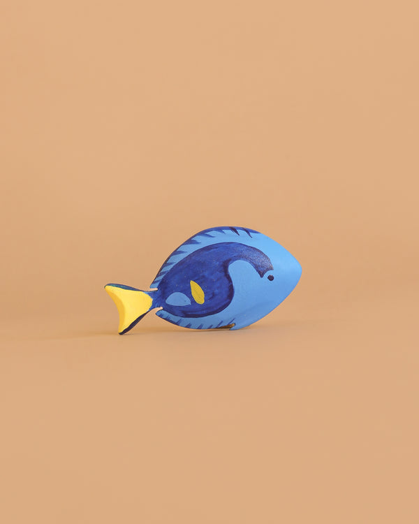 The Bumbu Handmade Wooden Royal Blue Fish, featuring blue and yellow painted details, is a sustainable Montessori toy displayed on a plain light brown background—perfect for mindful play.