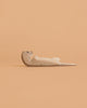 The Bumbu Handmade Wooden Otter Set features small, minimalist otters lying on their backs—eco-friendly toys ideal for thoughtful decor or imaginative play, shown against a peach-colored background.