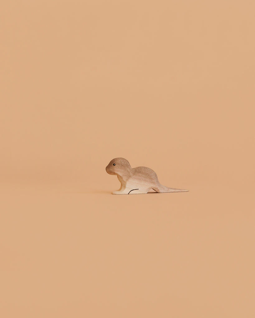 The Bumbu Handmade Wooden Otter Set is displayed against a plain light beige background, facing left. Its minimalistic composition emphasizes the eco-friendly charm of this handcrafted toy.