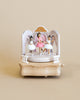 The wooden ballerina music box features a theatrical stage setting, adorned with delicate details. At the center stands a ballerina dressed in a pink dress, and surrounding her are three more ballerinas, each in a graceful stance, wearing white dresses. The ballerinas' features are lovingly painted, showcasing a range of skin tones, adding diversity and depth to the scene.