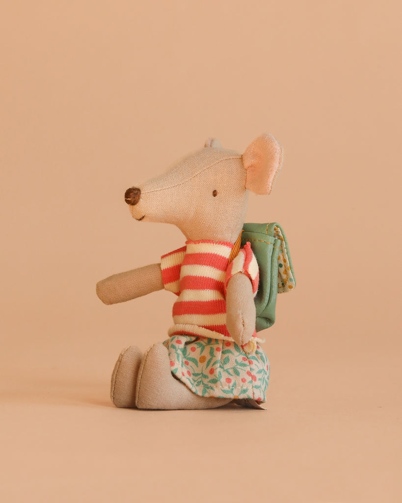 The Maileg Big Sister Tricycle Set features a mouse in a red and white striped shirt, floral skirt, and green backpack, seated on a beige background.