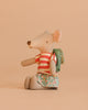 The Maileg Big Sister Tricycle Set features a mouse in a red and white striped shirt, floral skirt, and green backpack, sitting upright against a light beige background—ideal for pairing with the Maileg Tricycle Hanger.