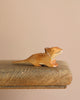The Bearded Dragon Wooden Animal is a small, brown dinosaur figurine crafted from sustainable hardwood. It features a long tail and short legs, resting on a wooden surface against a neutral backdrop. Its glossy finish with white accents enhances its charm, resembling an intricately crafted lizard toy.
