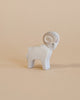 A small Ostheimer Ram figurine with a prominent spiral horn and detailed carving, standing against a plain beige background.