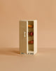A delightful cream-colored Maileg Kitchen Set with Grandma & Grandpa is shown with its fridge door slightly open, displaying miniature food items on the shelves. Perfectly sized for Maileg mouse furniture, this set adds a charming touch to any Maileg accessories collection. The background features a solid light beige color.