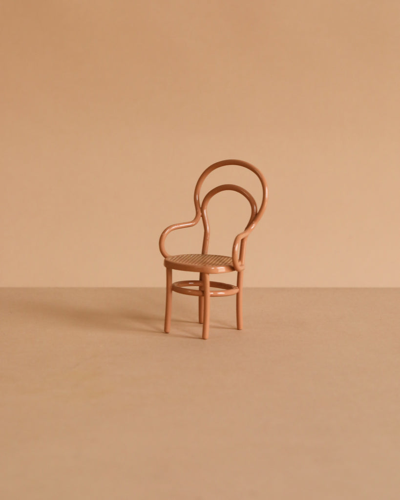 A small, light brown Maileg Dining Table & Chairs Set with curved backs and armrests sits on a matching beige surface against a plain beige background, perfectly Mouse Size for your miniature scenes.