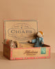 Nestled inside an open vintage cigar box labeled “Cigars” and “Havana,” the Maileg Family Time Set features two small mice—one lying under a blanket and the other sitting up in pajamas—set against a plain beige background.