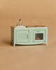 The Maileg Kitchen Set with Chef Mouse, part of the mouse playset collection, is a small mint green kitchen with a sink, cabinet, oven containing a toy item—perfect for miniature food accessories—shown on a beige background.