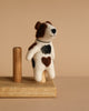 The Felt Finger Puppet: Jack Russell Terrier Dog features brown and black patches, including a heart-shaped patch on its side, and stands on a wooden platform against a beige background—ideal for imaginative play.