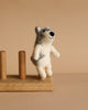 The Felt Finger Puppet: Alaskan Husky Dog, a small handmade item crafted from soft wool felt, stands upright on a wooden stand against a neutral beige background.