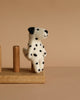 The Felt Finger Puppet: Dalmatian is a small, felted dog with black spots sitting upright on a wooden stand against a beige background—ideal for imaginative play or as a charming decorative piece.